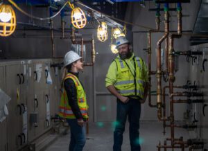 Employees from Williams Plumbing & Heating inspect the installation of copper piping in a hydronic boiler system.