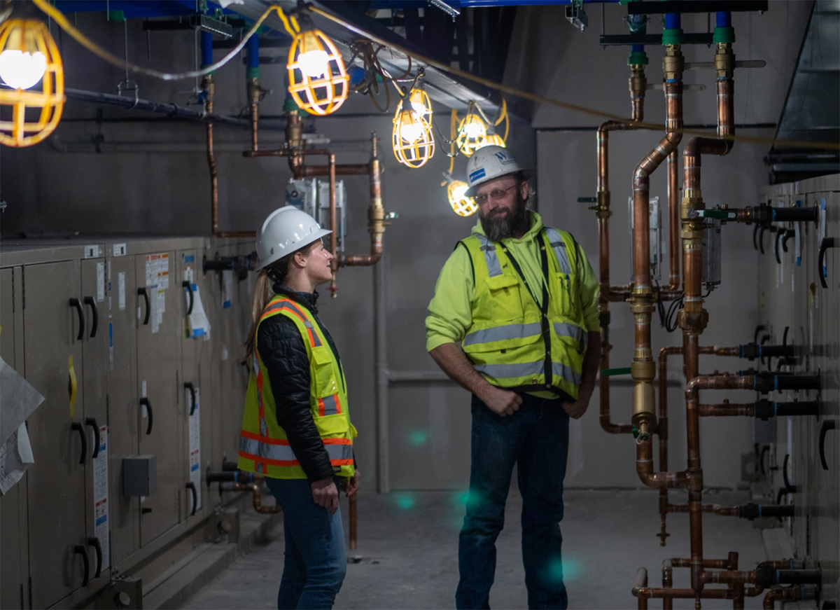 Employees from Williams Plumbing & Heating inspect the installation of copper piping in a hydronic boiler system.