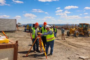Build Montana students getting instruction from an employee at COP Construction on the use of survey tools on a worksite.